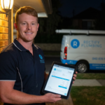 Emergency plumber arriving at Epping NSW home at night holding fixed price quote on tablet